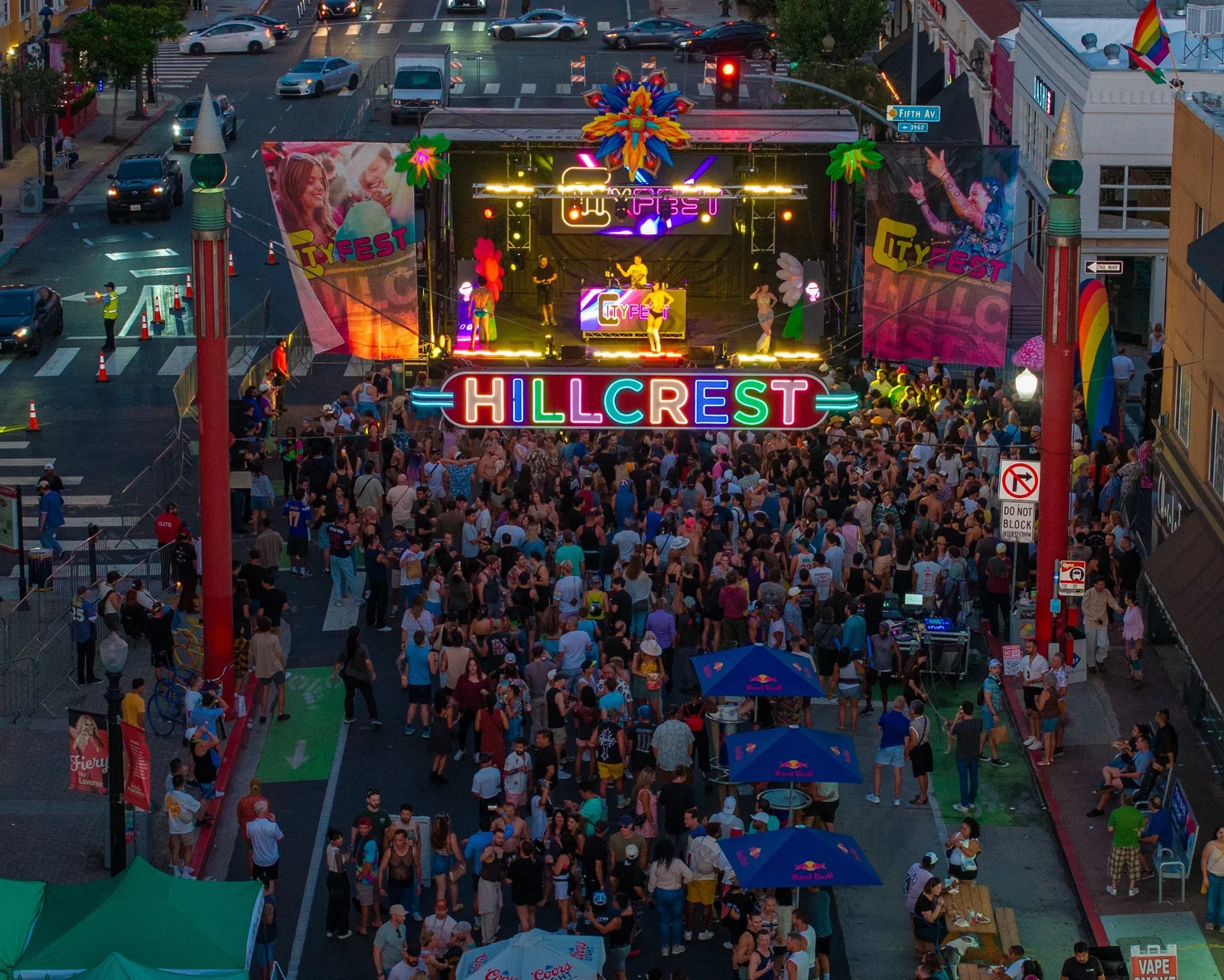 Pride Plaza on Normal Street packed at night, the Hillcrest sign lit over the crowd and the stage