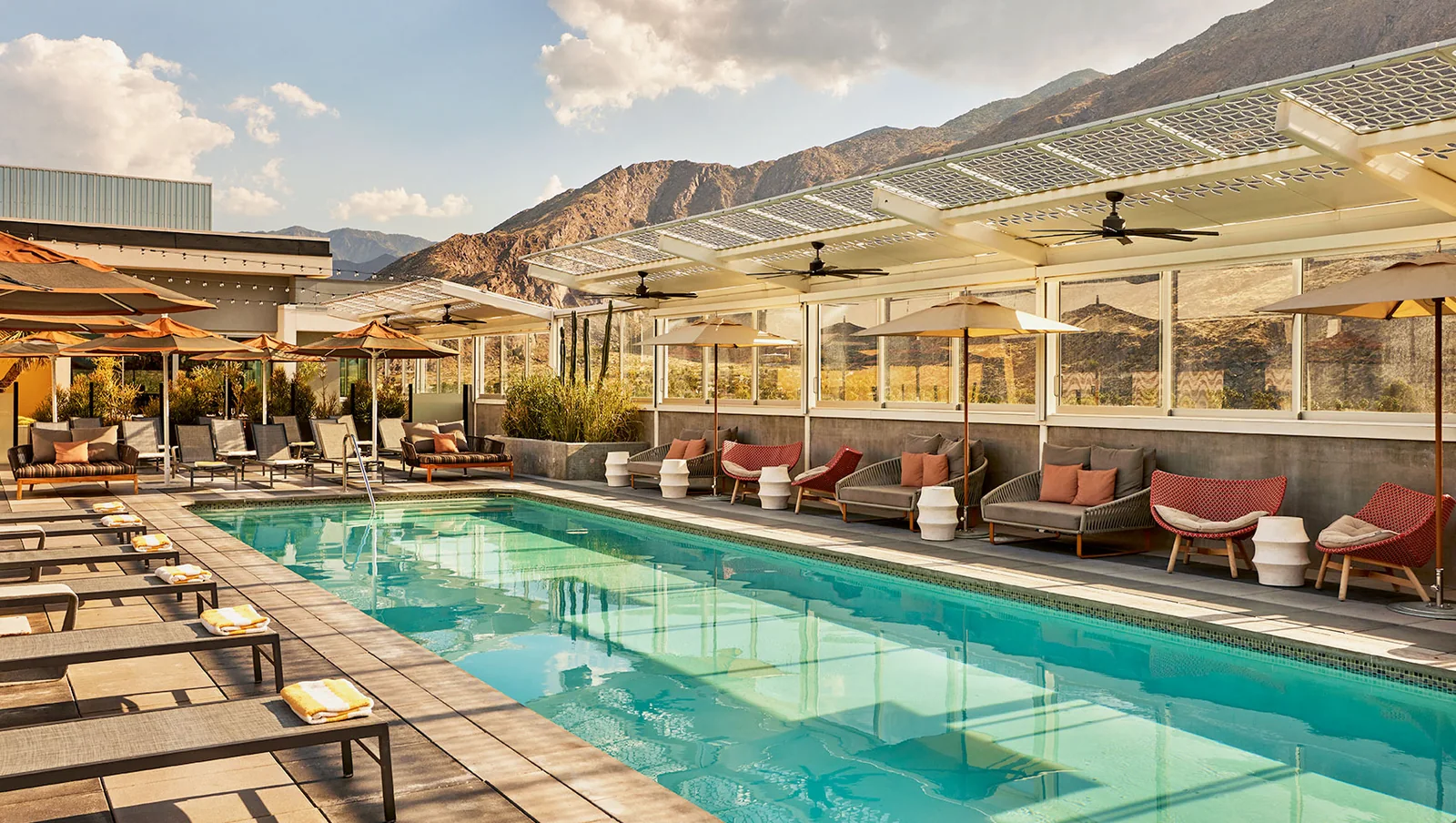 The rooftop pool at the Kimpton Rowan, daybeds along the edge and the San Jacinto mountains right behind the rail
