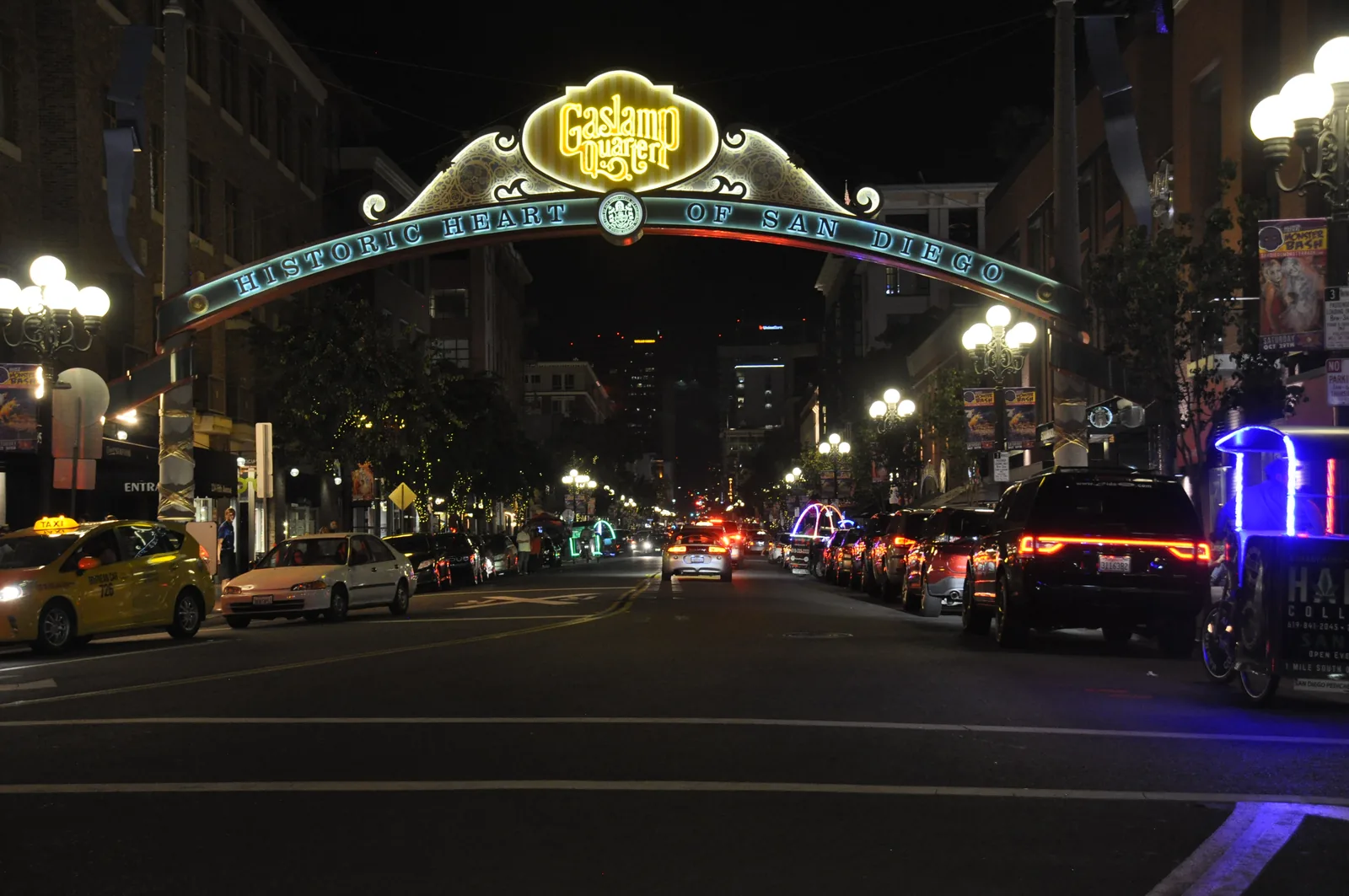 The Gaslamp Quarter sign lit up over Fifth Avenue at night, the street full of cars and light underneath it